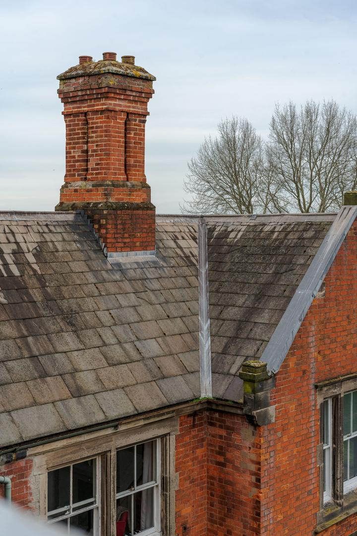 Tall brick chimney and decorative masonry above a slate roof